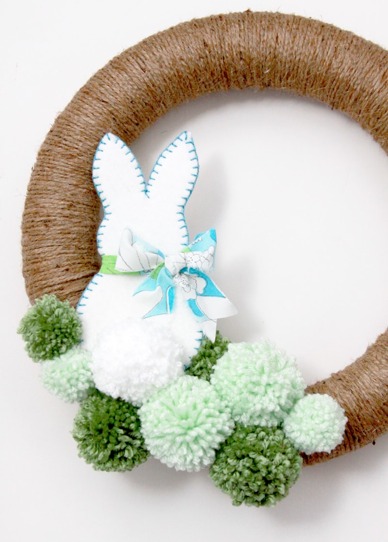 Spring Pom Pom Wreath - so cute! Tutorial on { lilluna.com } Supplies include a foam wreath, fabric, yarn, twine, felt, and mini Easter eggs.