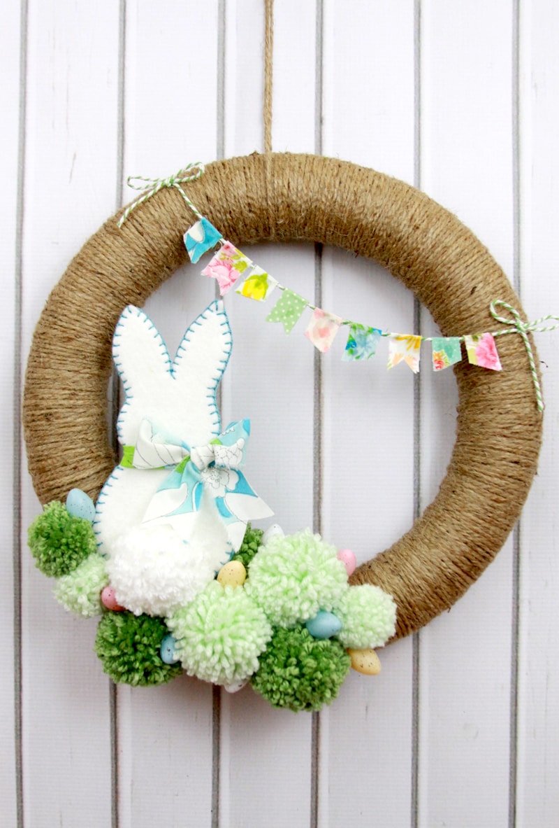 Spring Pom Pom Wreath - so cute! Tutorial on { lilluna.com } Supplies include a foam wreath, fabric, yarn, twine, felt, and mini Easter eggs.