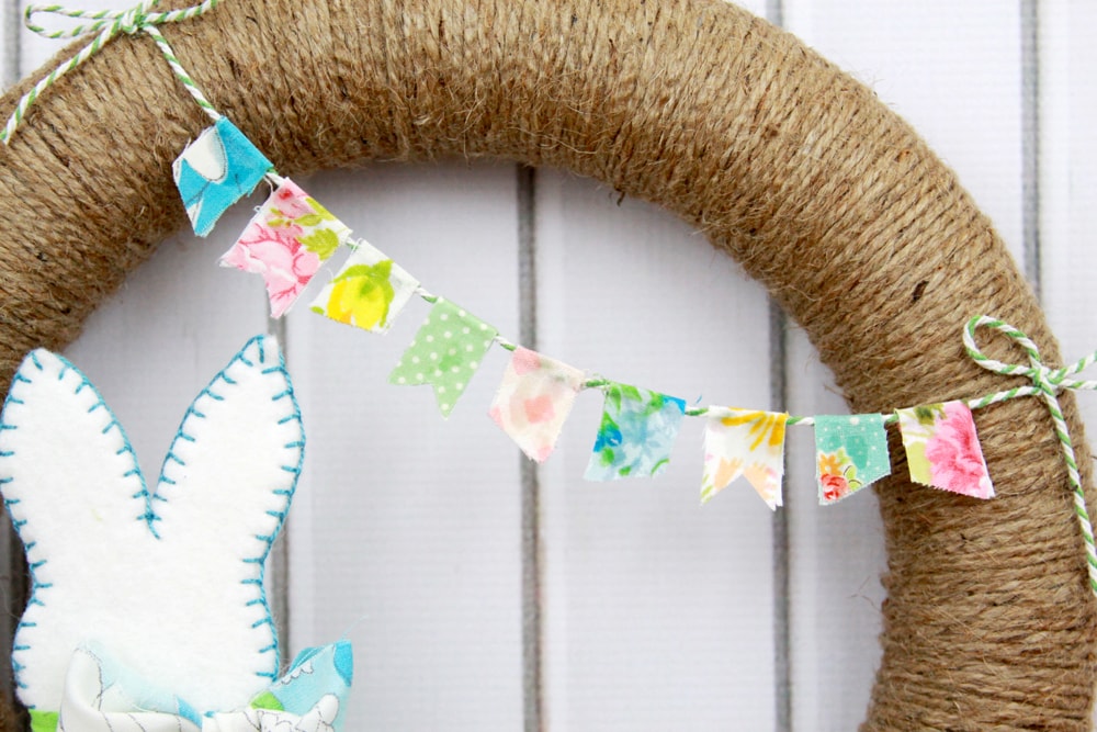 Spring Pom Pom Wreath - so cute! Tutorial on { lilluna.com } Supplies include a foam wreath, fabric, yarn, twine, felt, and mini Easter eggs.