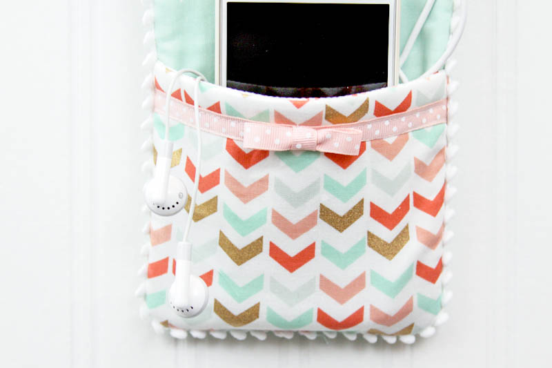 DIY Phone Charger Holder Holder - LOVE this idea!! Supplies needed include - fabric, fusible fleece, ribbon, pom pom trim, and a shower curtain grommet.