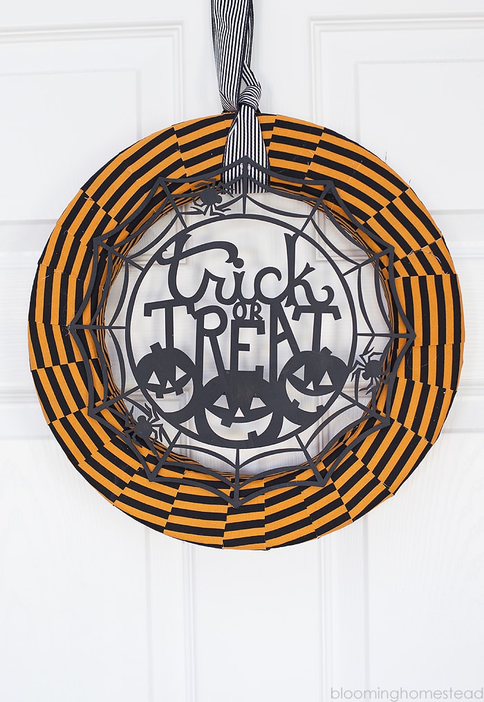 Trick or Treat Wreath hanging with black and white ribbon on a front door.